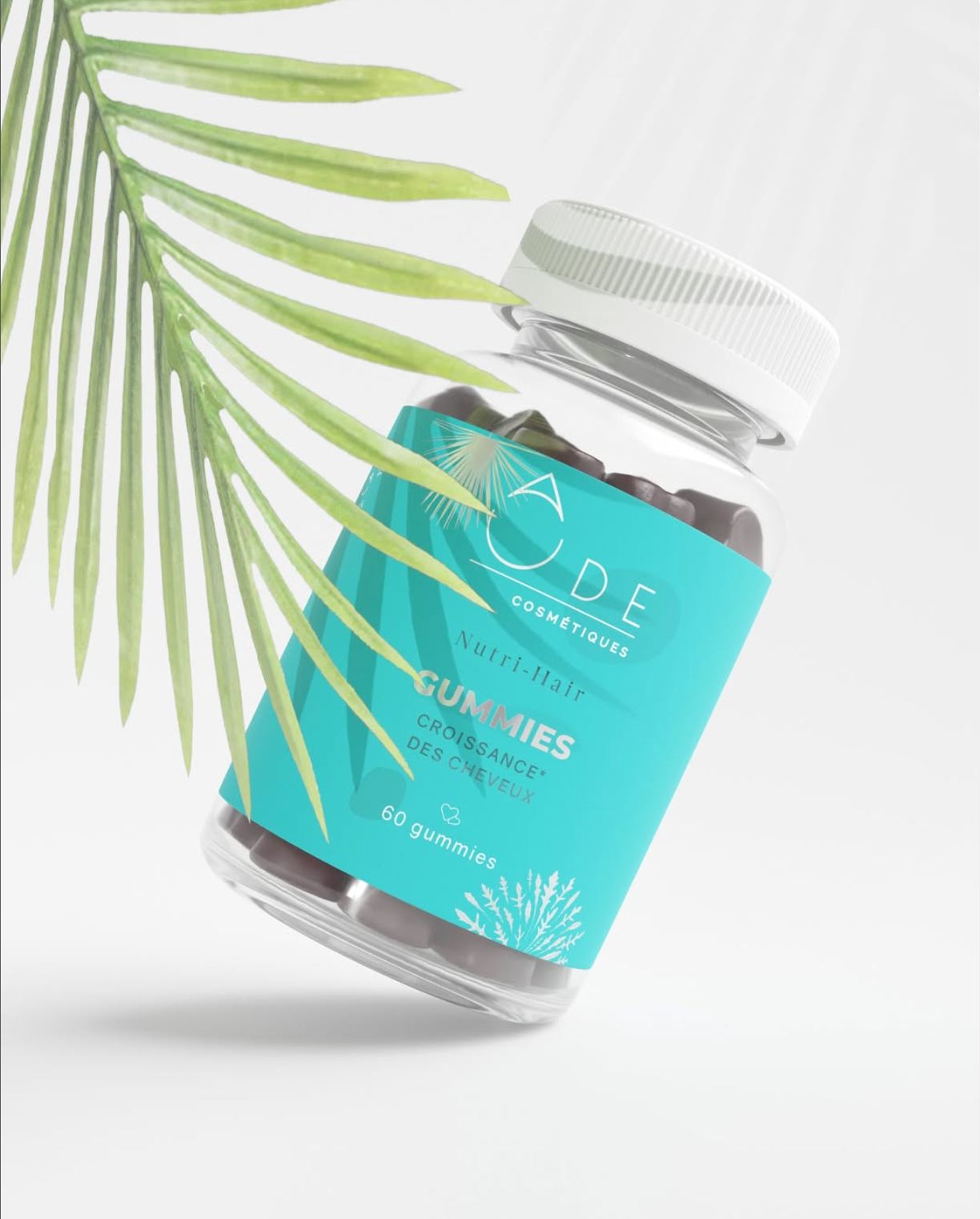 Une bouteille de gummies pour la croissance des cheveux, de couleur turquoise, avec une étiquette indiquant 'Gummies Croissance des Cheveux' et contenant 60 gummies, posée à côté d'une feuille verte en fond blanc.