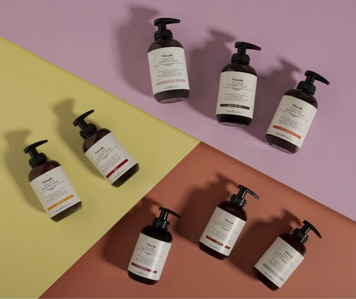 Différents flacons de crème parfumée avec des étiquettes colorées sur un fond coloré pastel.