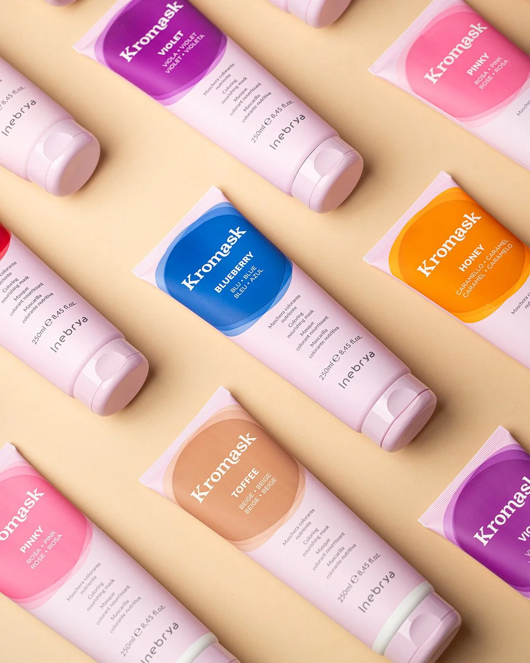 Kromask inebrya. Gamme de masques en tube de différentes couleurs avec écriture en anglais et français, posés sur un fond beige.