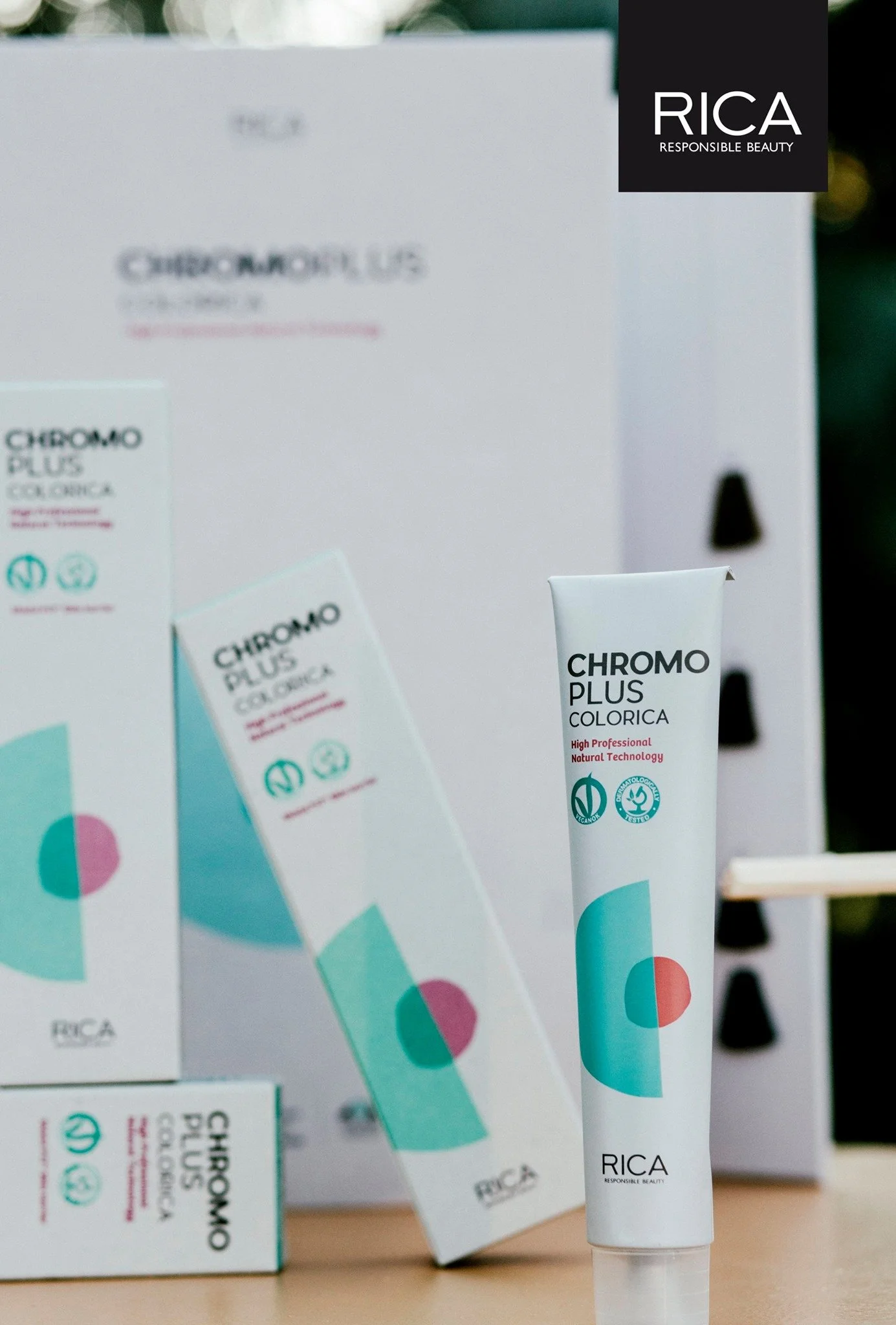 Tube de crème de coloration capillaire RICA Chromo Plus sur une table, avec l'emballage et un coffret en arrière-plan.