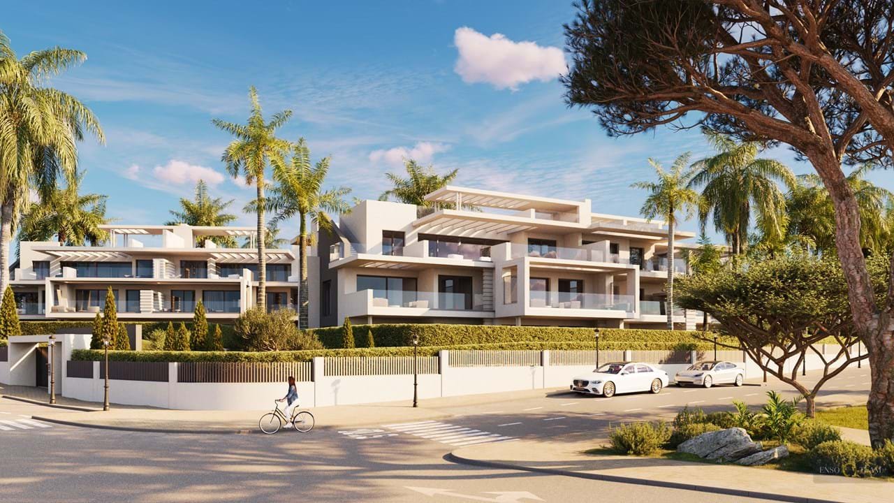 Modern apartment buildings with balconies surrounded by palm trees and a person cycling on a sunny day.
