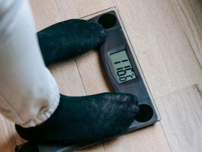Person standing on a digital bathroom scale, weighing 116.3 pounds.