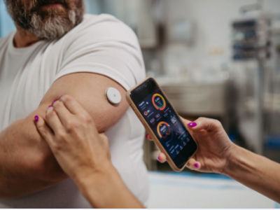 Person with a glucose monitor on their upper arm receiving data on a smartphone.