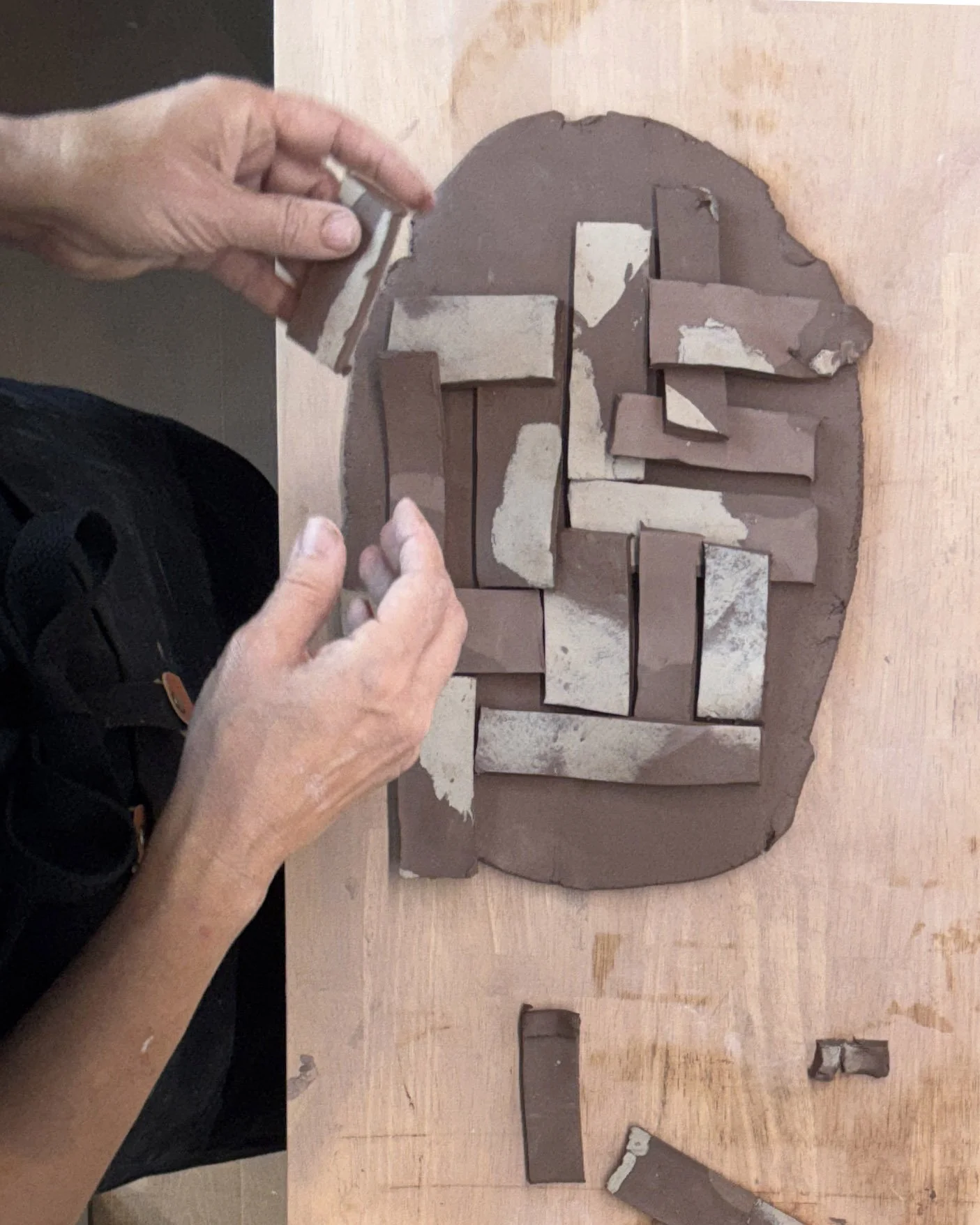 Contrasting clay pieces are arranged on a base slab to build the pattern.