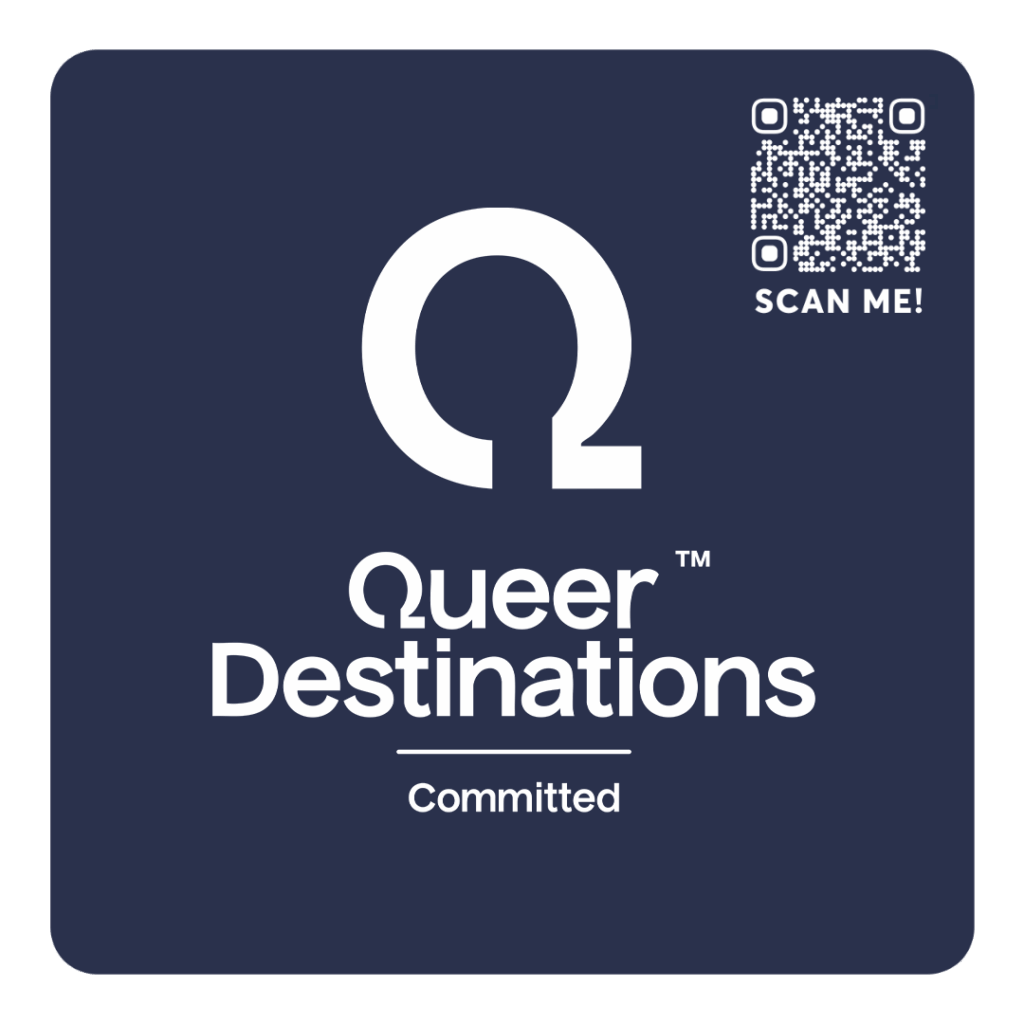 A dark blue square social media tag with a large white Greek letter omega symbol at the top, the words 'Queer Destinations' in bold white text below, a small horizontal line, and the word 'Committed' underneath. In the top right corner, there's a QR 