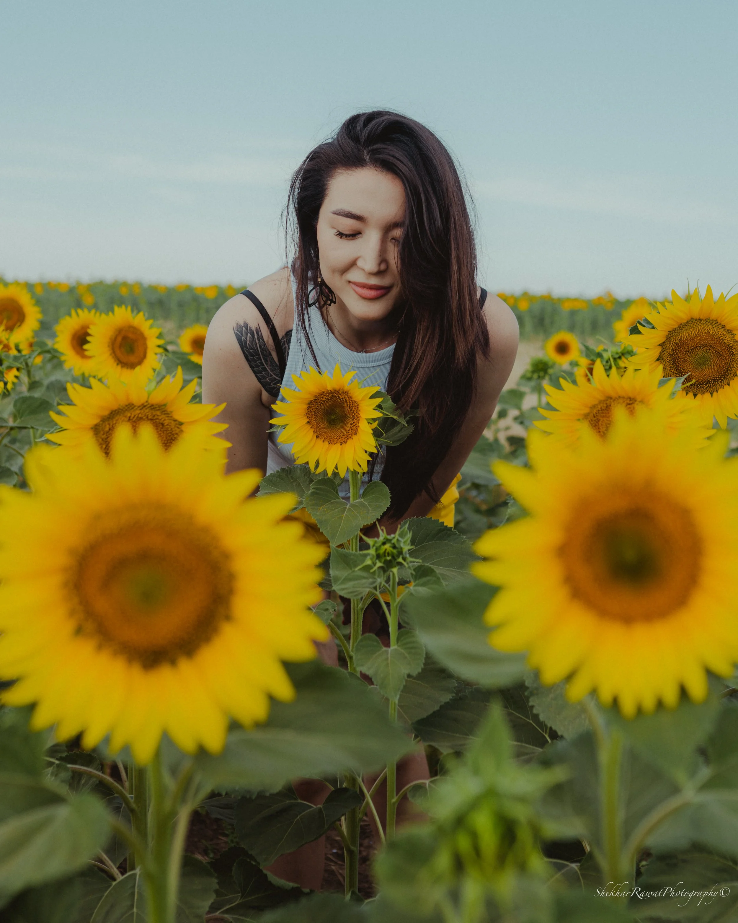 Smiling woman with eyes closed in a sunflower field, summer portrait by Melbourne photographer Shekhar Rawat