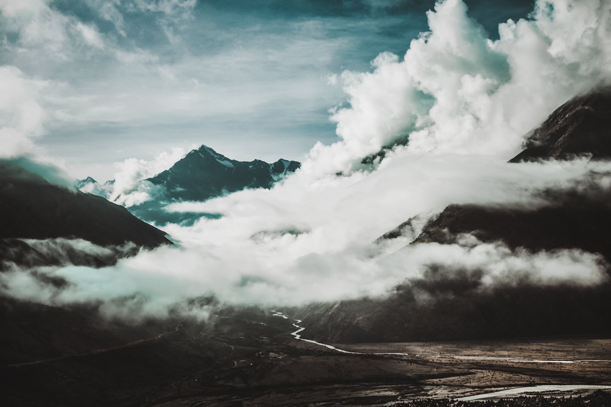 Snow-capped mountains and river valley under clouds, landscape photography by Shekhar Rawat
