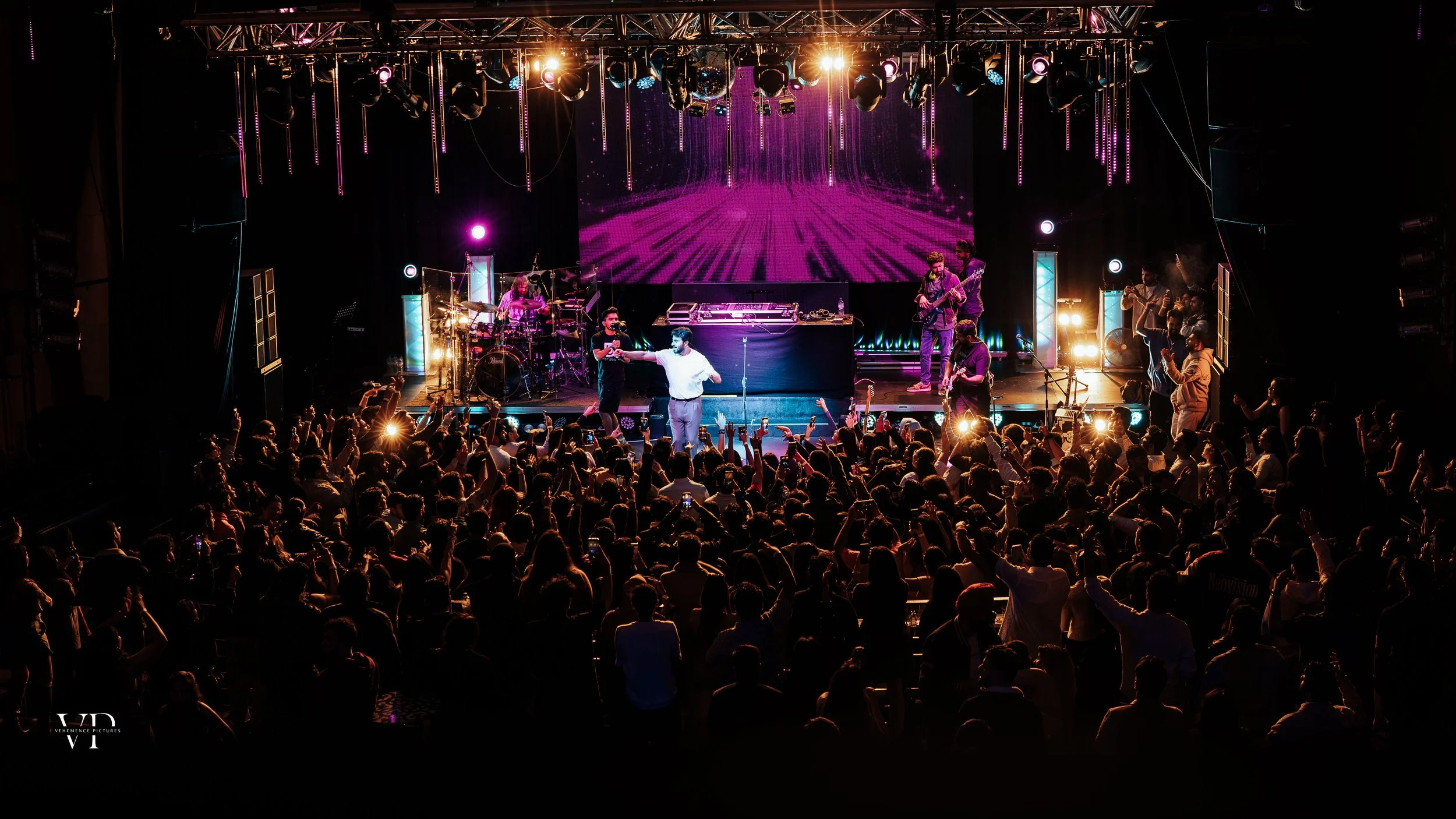 Live concert with a band on stage and a dancing crowd, event photography by Shekhar Rawat, Melbourne