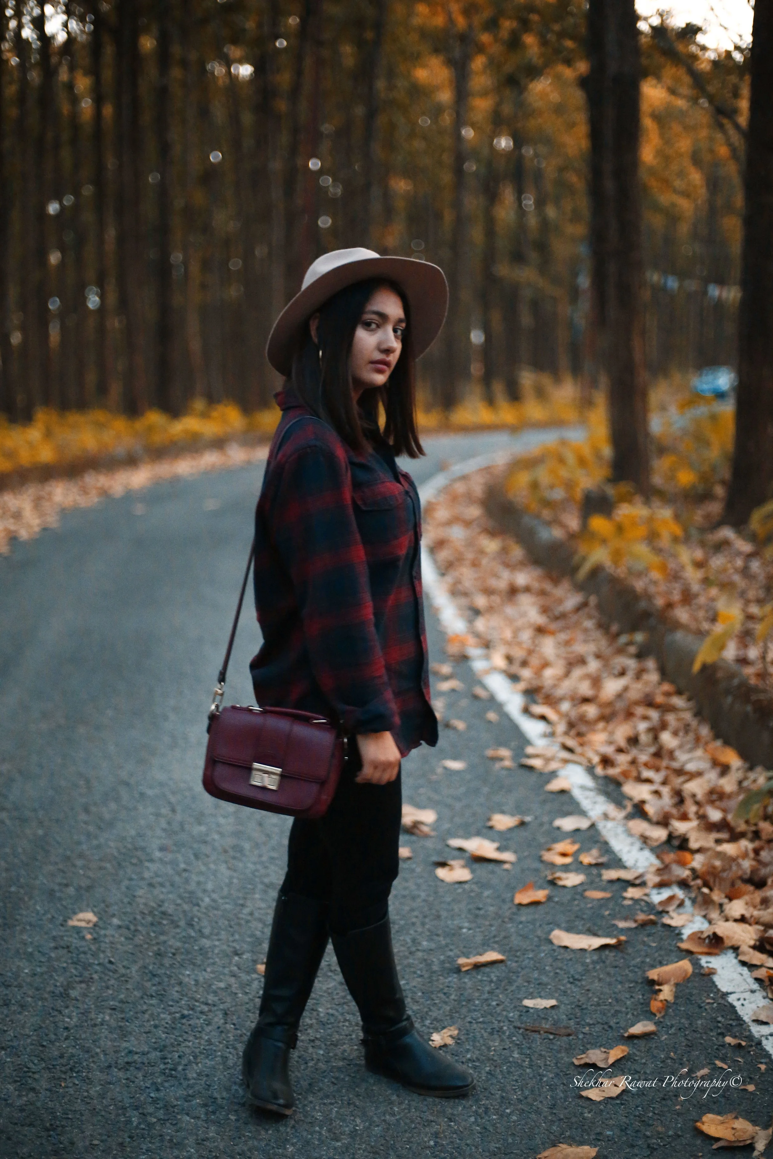 Model in a hat and plaid shirt on an autumn forest road, lifestyle portrait by Melbourne photographer Shekhar Rawat