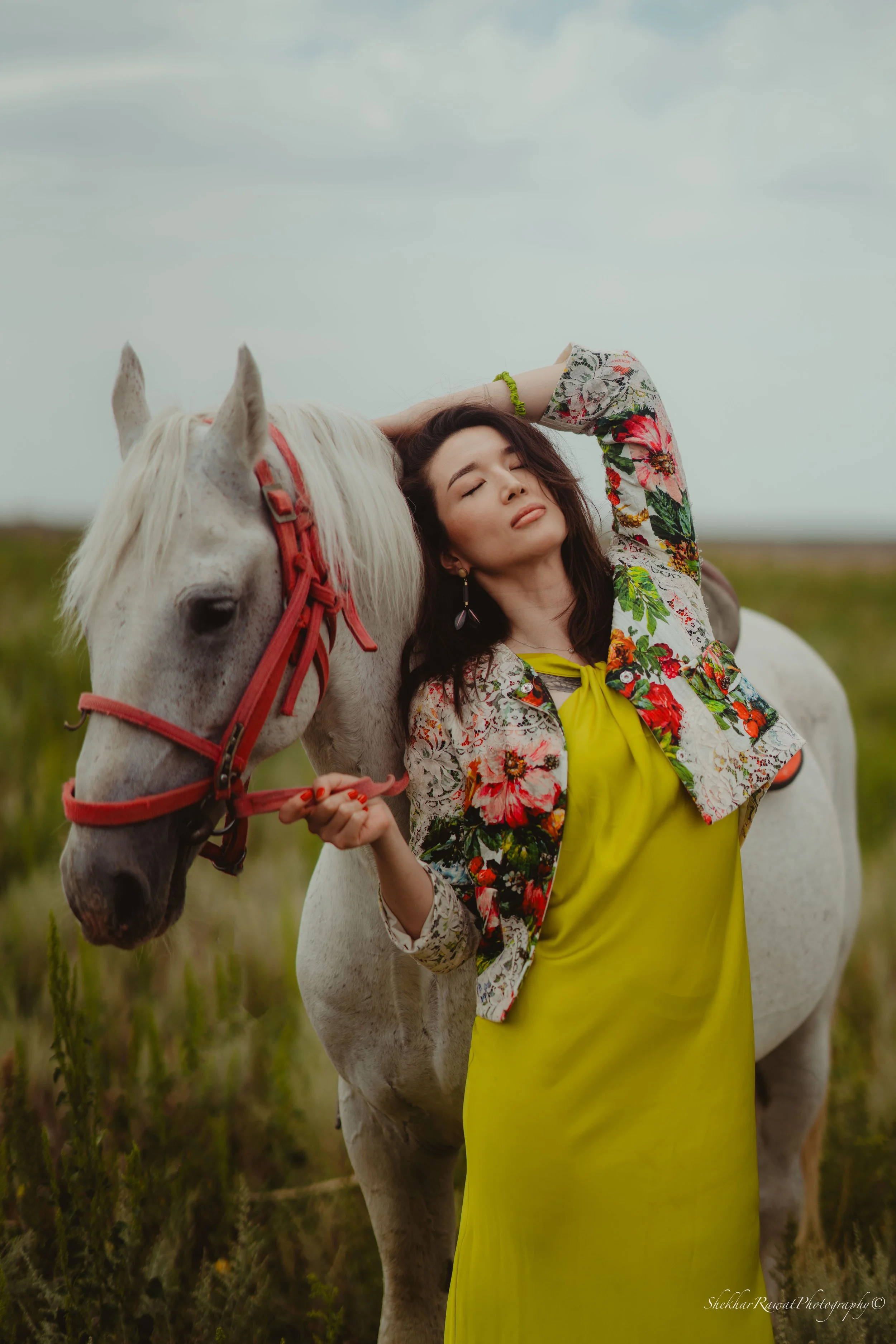 Model in a floral jacket with a white horse in a field, fashion photography by Shekhar Rawat