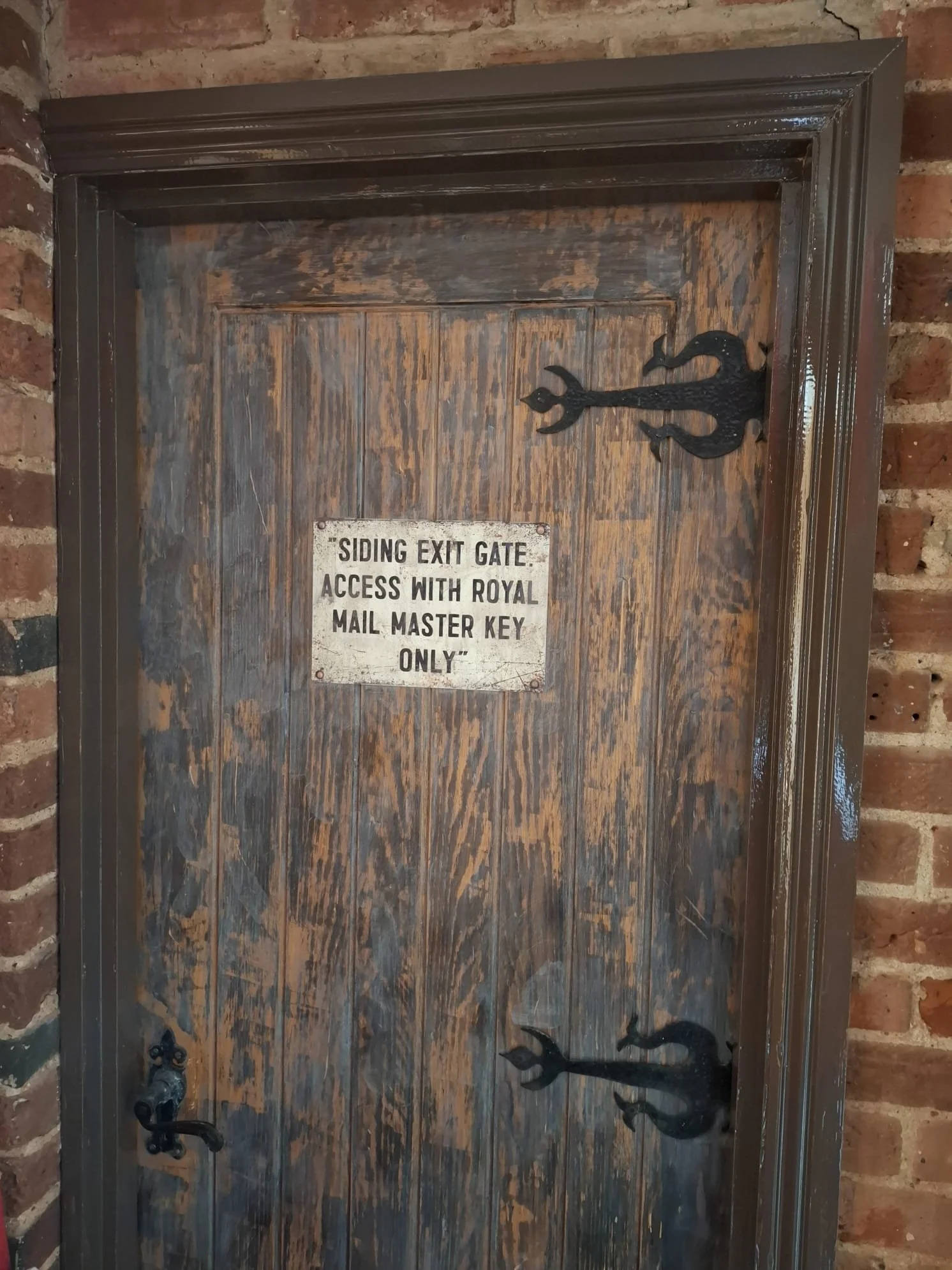 A rustic brown door with a sign saying access with royal mail key only