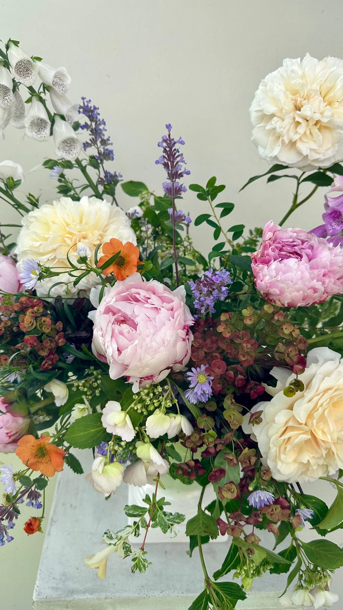 A colorful flower arrangement with white, pink, purple, and orange flowers on a white surface.