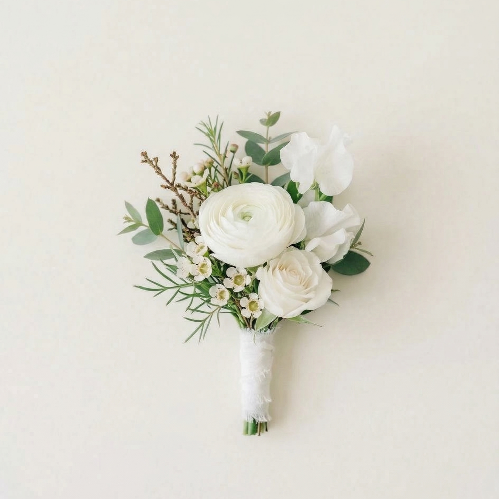 White floral boutonniere with roses, ranunculus, greenery, and small filler flowers on a white background.