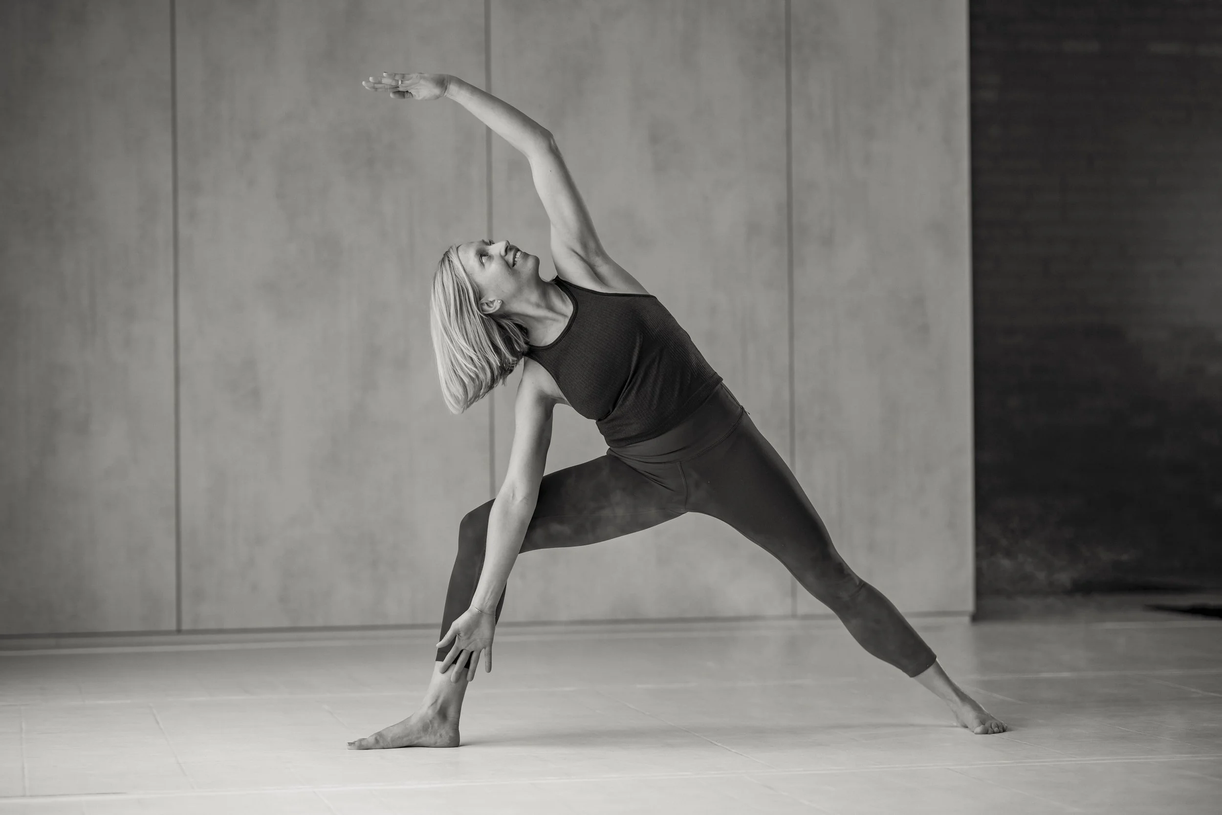 People practicing yoga in a studio with mirrors and exercise mats.