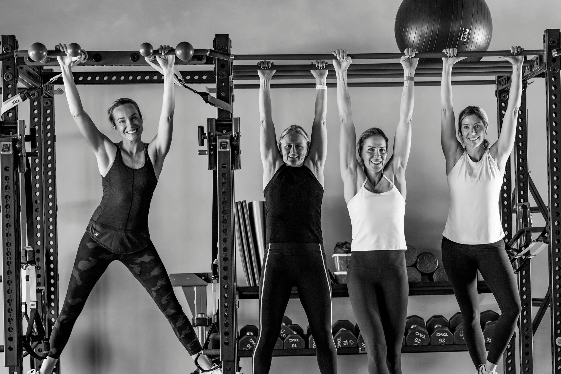 Woman exercising with dumbbells on a mat in a gym.