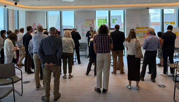 The Workshop participants in a group, three rows deep and about 10–15 people wide, lifting their fists to celebrate two days of hard work.