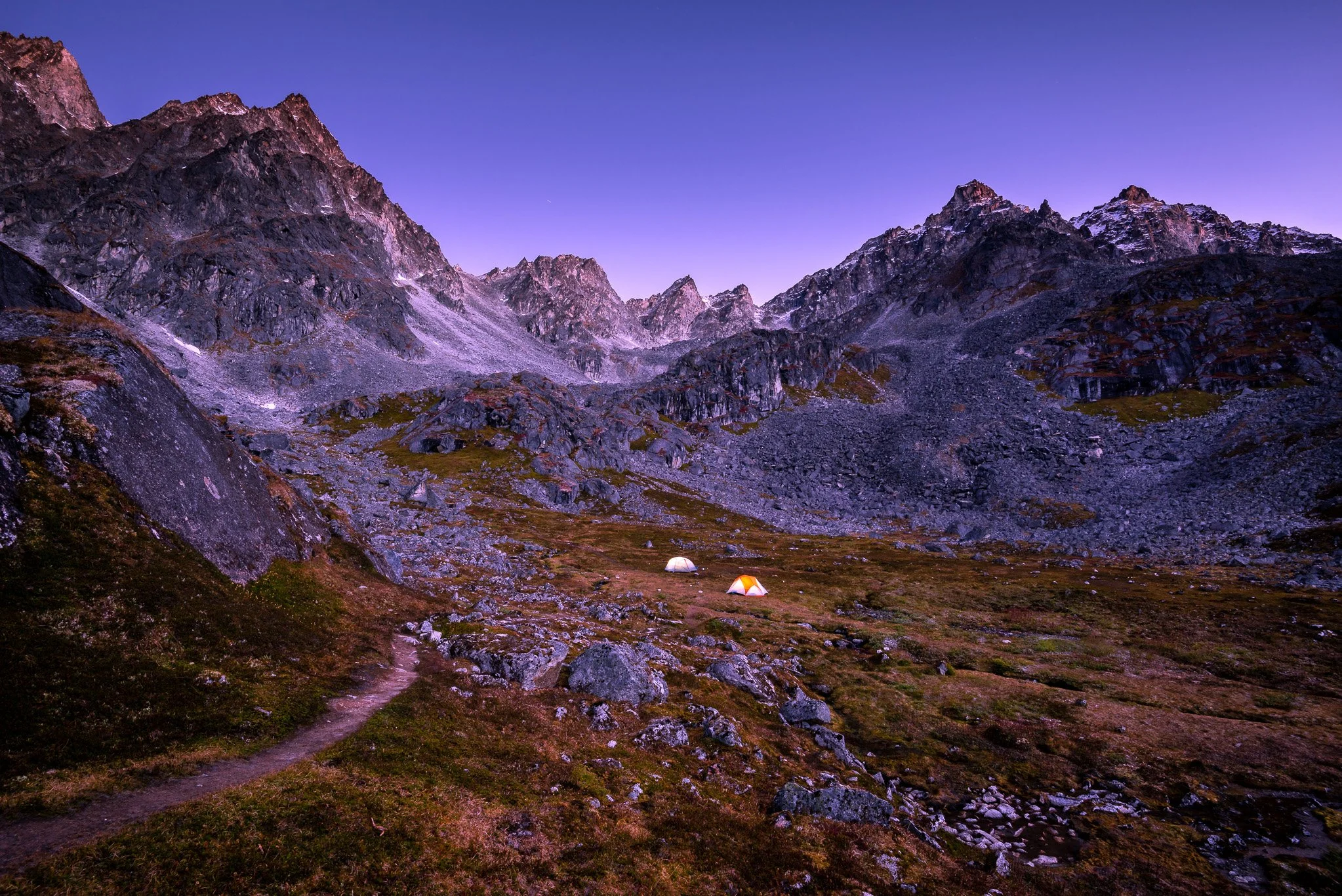 Two tents in the valley of rocky mountain peaks.