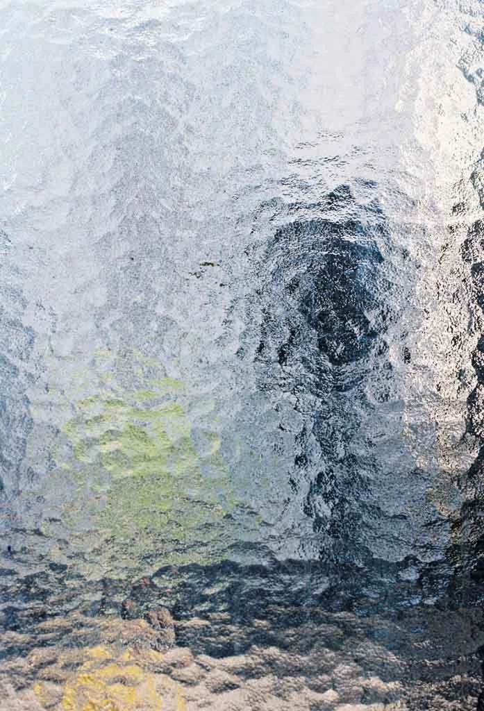 Poster mit dem Motiv von Ornamentglas aus nächster Nähe fotografiert. Die Farben des Bildes sind überwiegend Blautöne. Die Scheibe befindet sich am Treppenaufgang des Kottbusser Tor hoch zur U1/U3. 