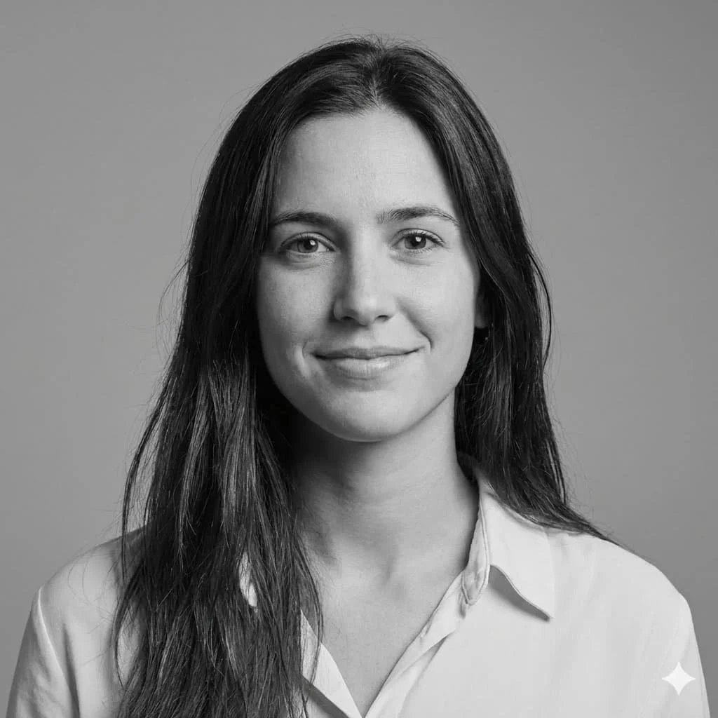 Black and white portrait of a woman with long dark hair, wearing a light-colored shirt, smiling gently, against a plain background.