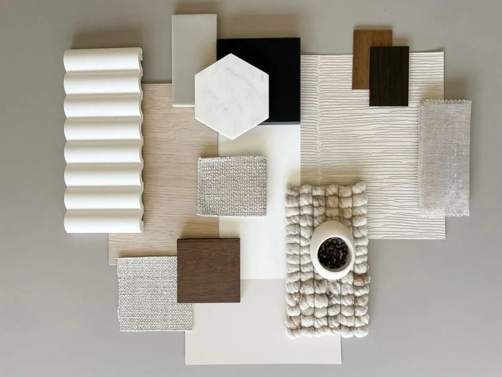 An assortment of interior design material samples, including wood, fabric, marble, and textured surfaces, arranged on a flat surface for a design project.
