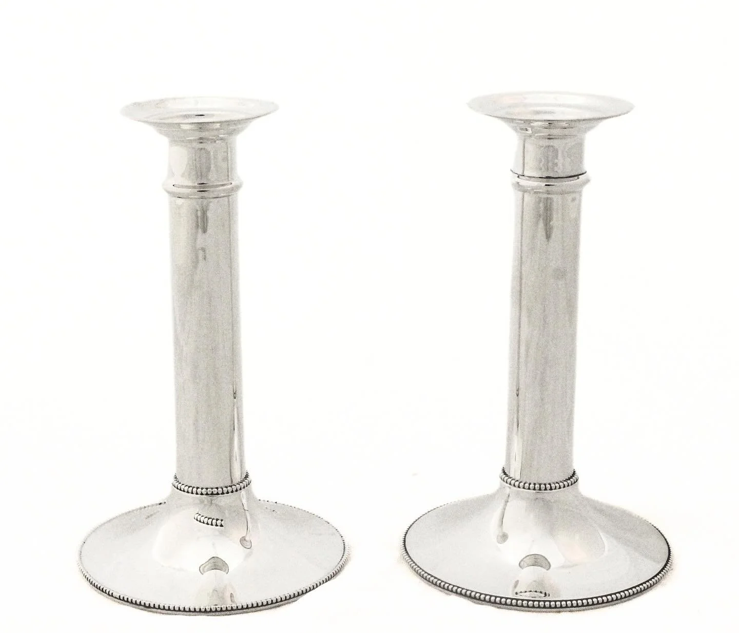 Elegant and understated design in fine sterling silver, featuring circular bases with a delicate beaded border along the rim and additional beading accentuating the junction where the base meets the shaft. The tall, tapering shafts rise with smooth, 
