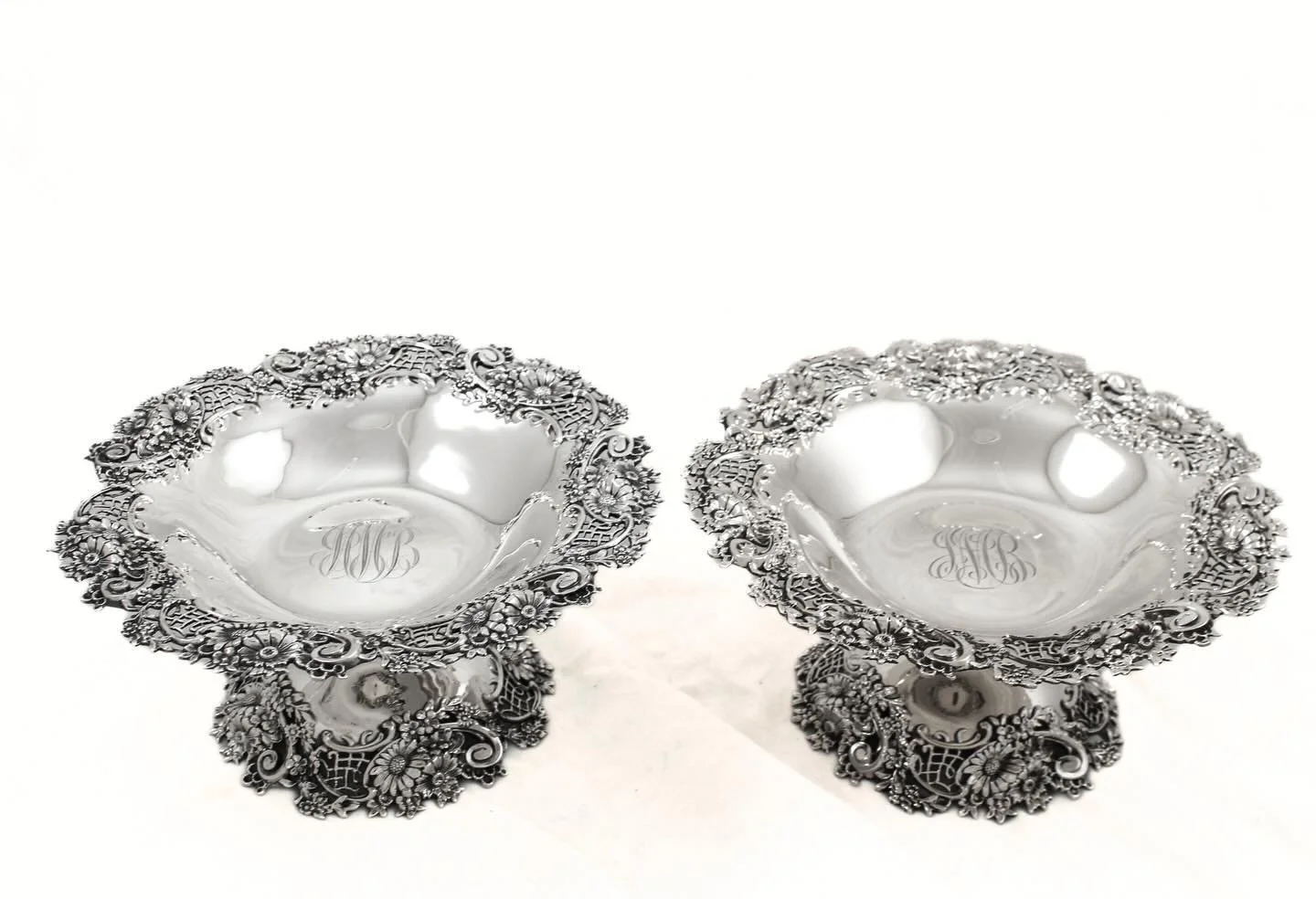 A magnificent pair of richly repouss&eacute; sterling silver compotes by Black, Starr &amp; Frost, marked B.S. &amp; B. Co. Deeply chased florals, scrolling acanthus, and intricate latticework wrap the flared bowls and cascade down the sculptural ped