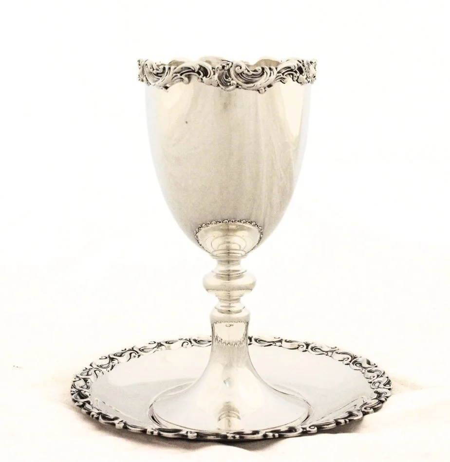 As the week winds down and the candles are nearly ready to be lit, a beautiful sterling silver Kiddush goblet and matching plate help set the tone for the Shabbat table. With its graceful baluster stem and richly detailed scrollwork along the rim, th