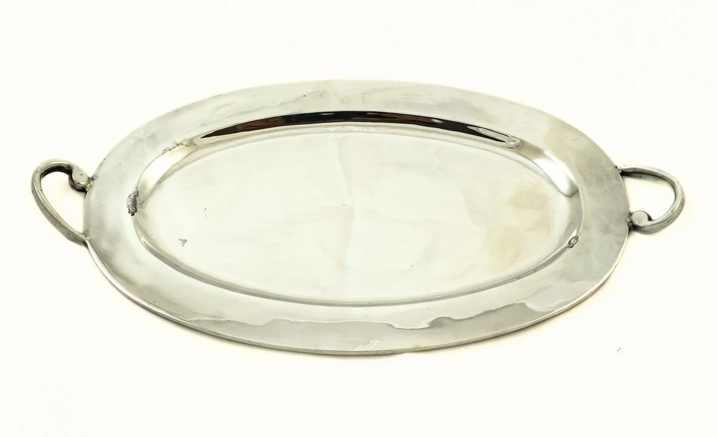 A striking mid-century modern sterling silver tray, distinguished by its clean oval form and sculptural scroll handles. The restrained design, free of excessive ornament, reflects the elegant simplicity that defined mid-20th-century silver. Subtle ha
