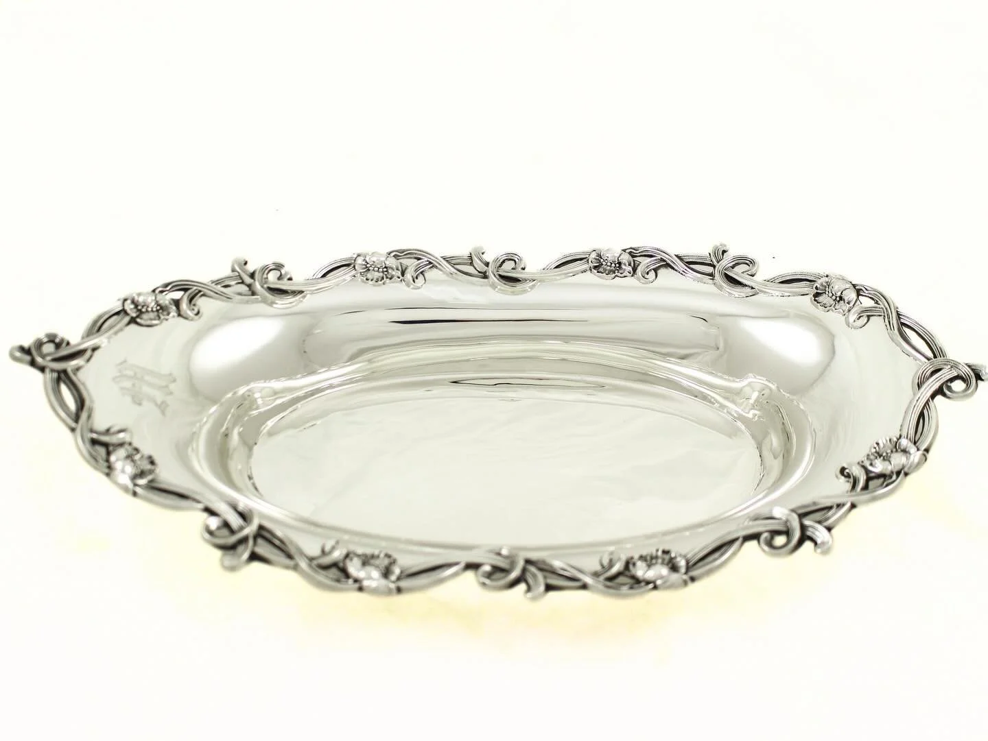 A proper table starts with proper pieces&mdash;and this one does the talking for you.
Elegant oval sterling silver breadbasket by Woodside Sterling Co., featuring a beautifully executed flowing vine-and-floral rim. The border has that classic early 2