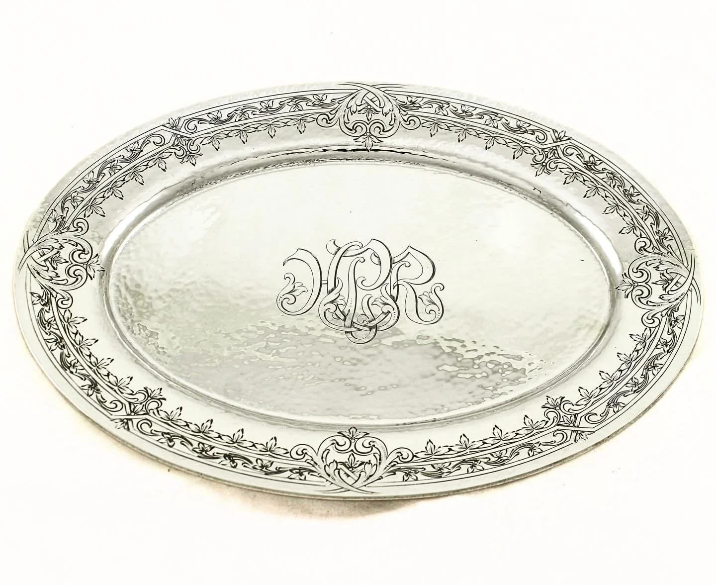 Elegance, craftsmanship, and tradition &mdash; all captured in sterling silver.
This hand-hammered oval platter features a beautifully engraved border with flowing Art Nouveau-inspired detail, centered by an elaborate monogram that speaks to a bygone