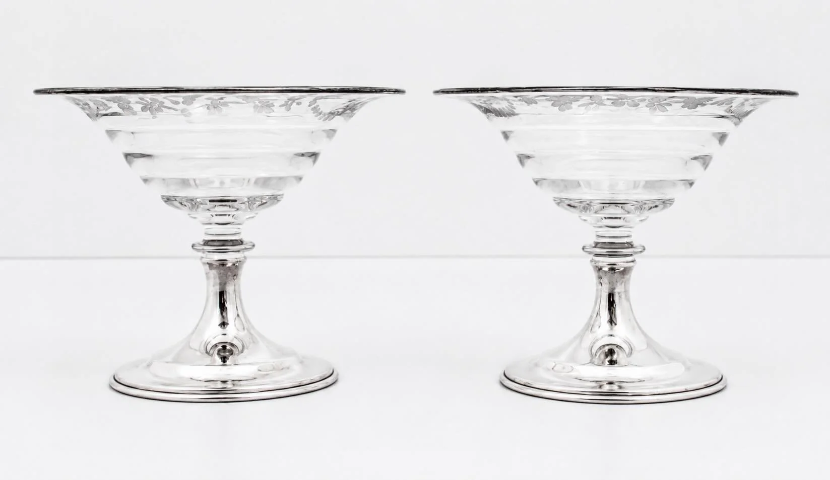 An elegant pairing of American brilliance and sterling silver craftsmanship.
This exceptional pair of sterling silver and crystal compotes was manufactured by the renowned Hawkes Glass Company of Corning, New York &mdash; widely regarded as the premi