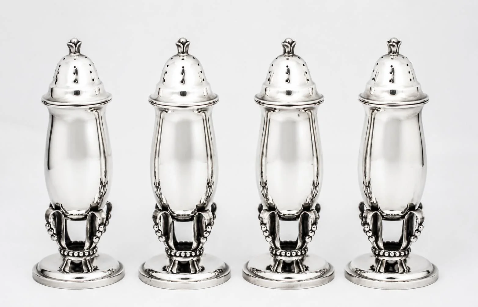 Four matching Art Deco sterling silver salt shakers &mdash; bold in scale, architectural in form, and impossible to overlook.

With their streamlined silhouette and striking stepped base detail, these extra large shakers embody the elegance and moder