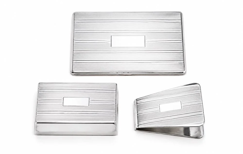 Monday mornings deserve a little refinement.

Start the workweek with this handsome Art Deco sterling silver desk suite, comprised of a stamp box, paper clip, and double standing frame. With its clean geometric lines, engine-turned decoration, and ti