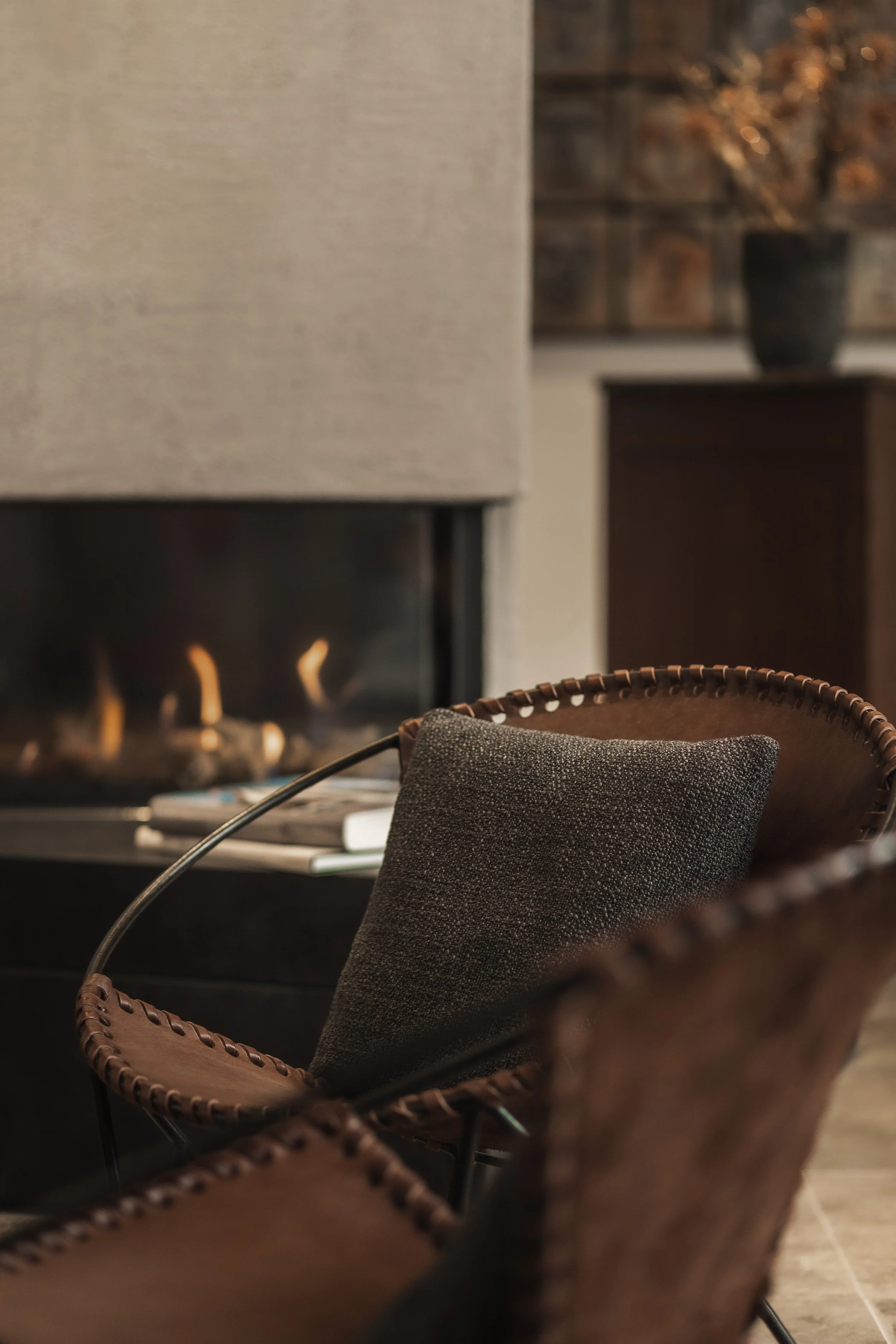 Ein wohnliches Wohnzimmer mit einem Kamin, einem Sessel mit Kissen und einem Beistelltisch mit Zeitschriften.