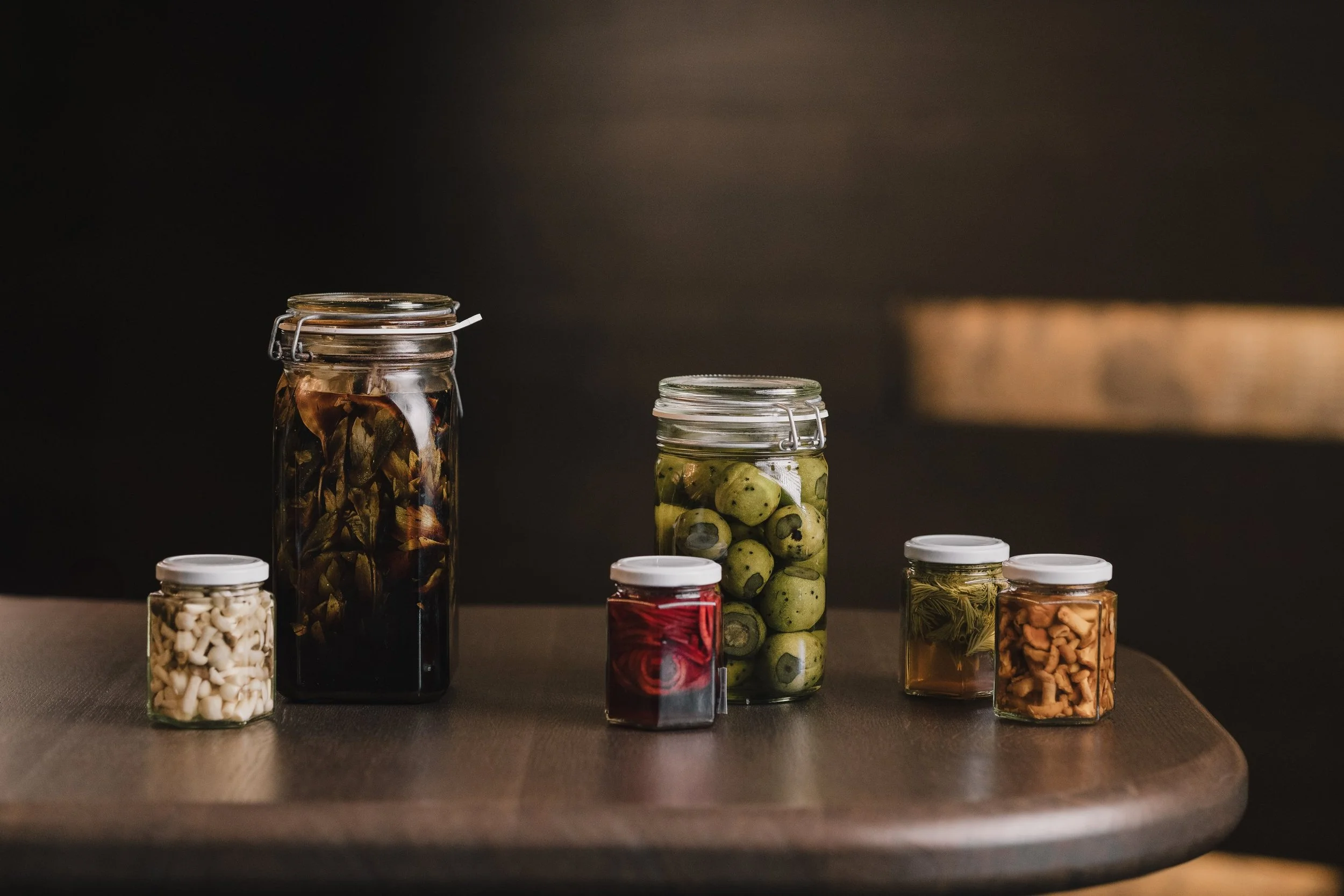 Verschiedene Gläser und Behälter mit eingelagerten Lebensmitteln auf einem Holztisch