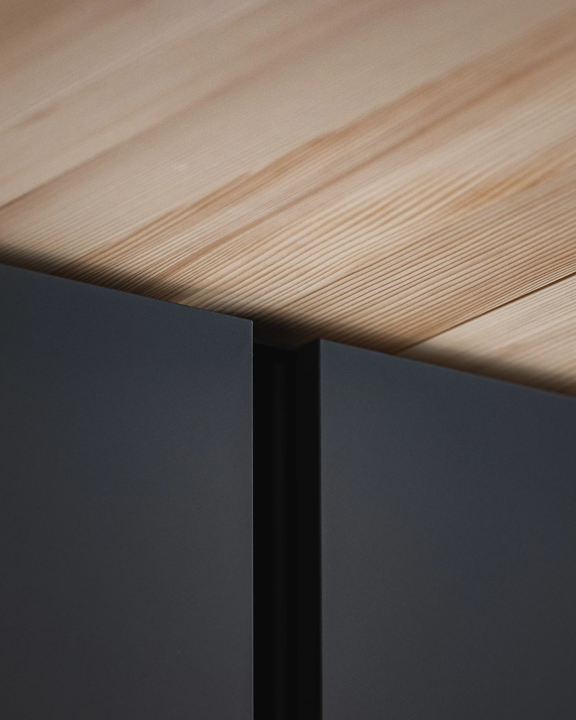 Nahaufnahme eines dunklen, modernen Möbels mit Holzdekor an der Oberseite.