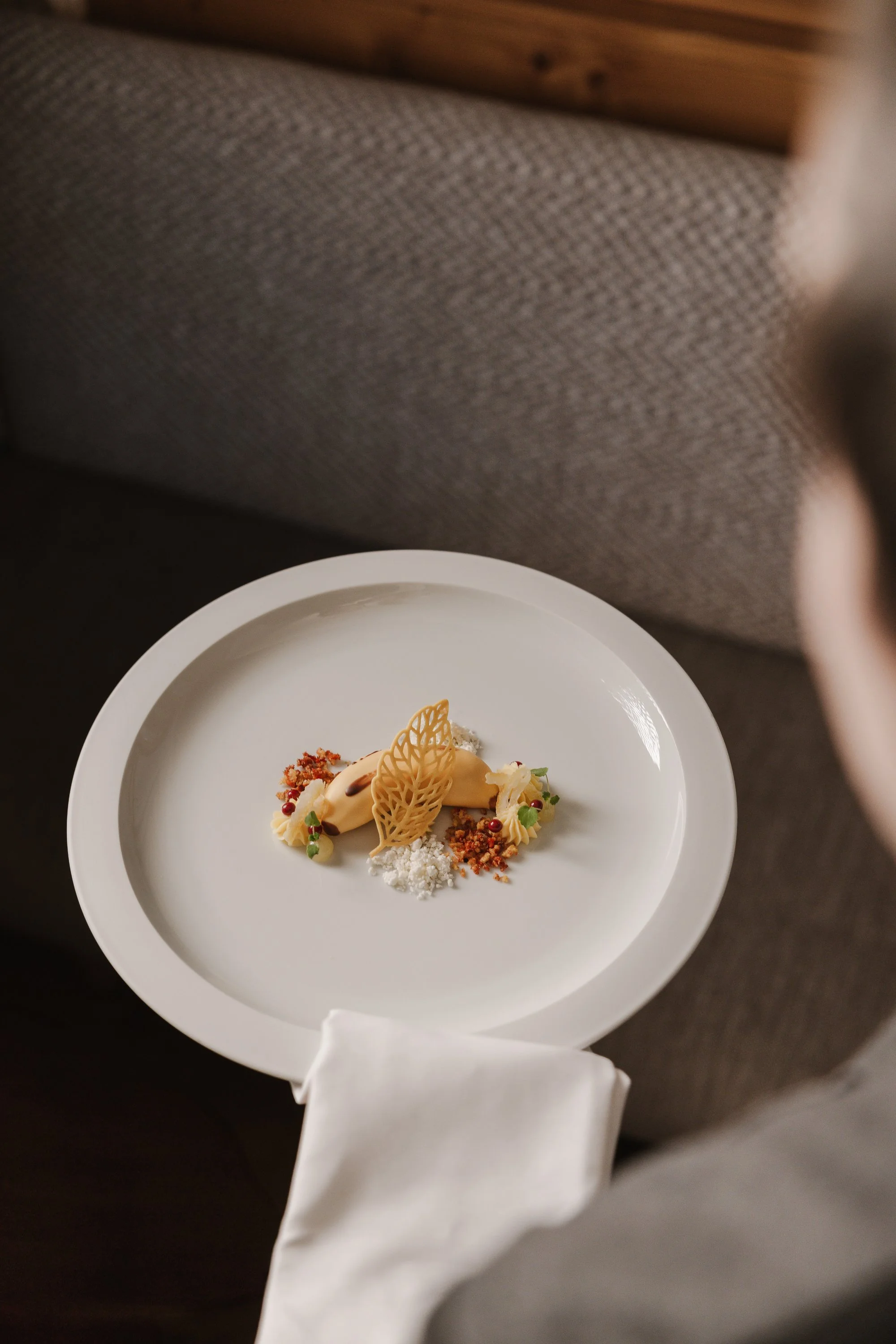 Feines Dessert auf einem weißen Teller, bestehend aus verschiedenen dekorativen Elementen und Dekorationen.