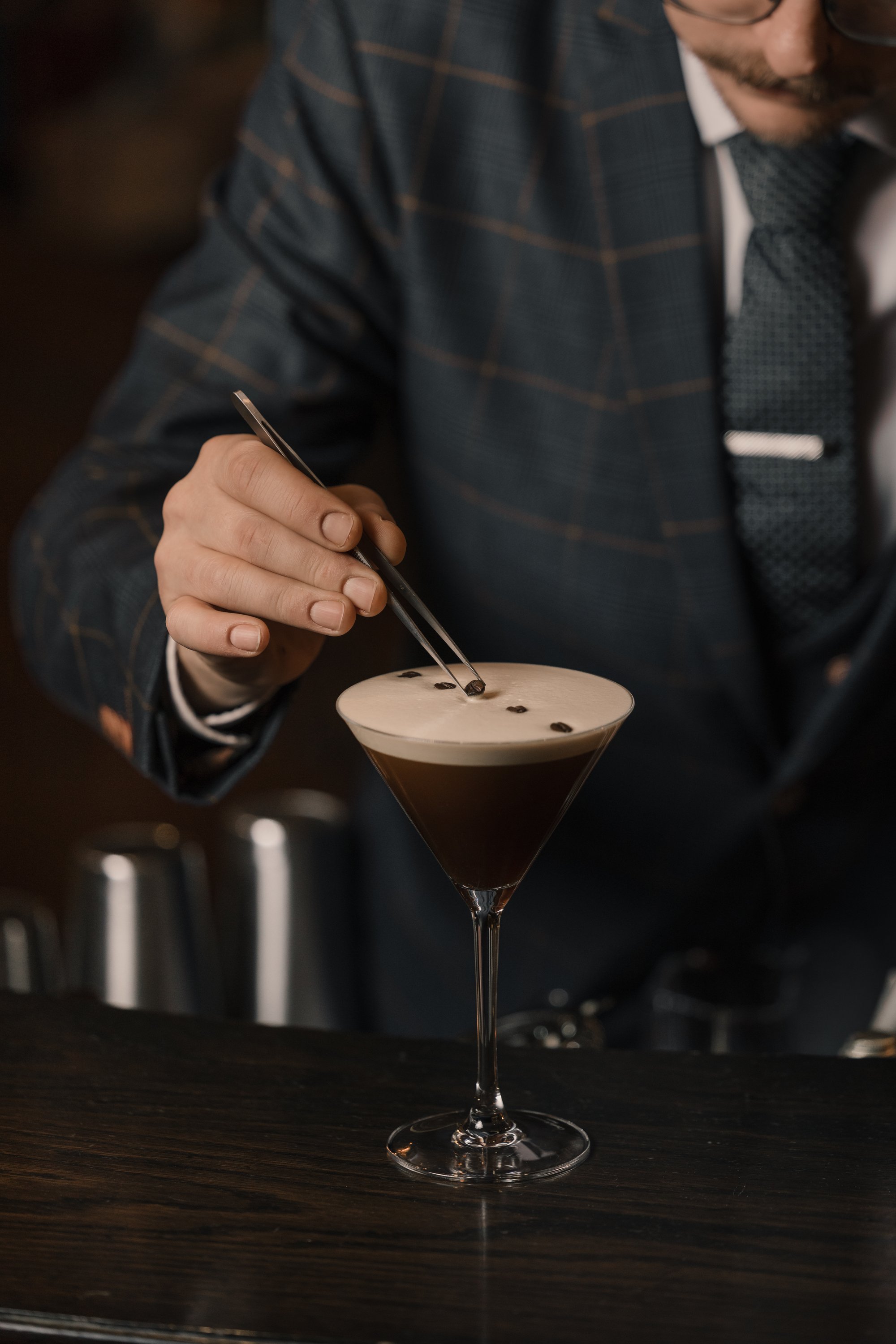 Mann in Anzug garniert einen Kaffee-Cocktail mit Kaffeebohnen