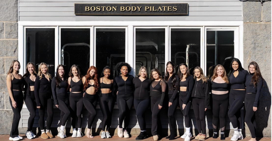 Group of women dressed in black fitness attire outside Boston Body Pilates studio.