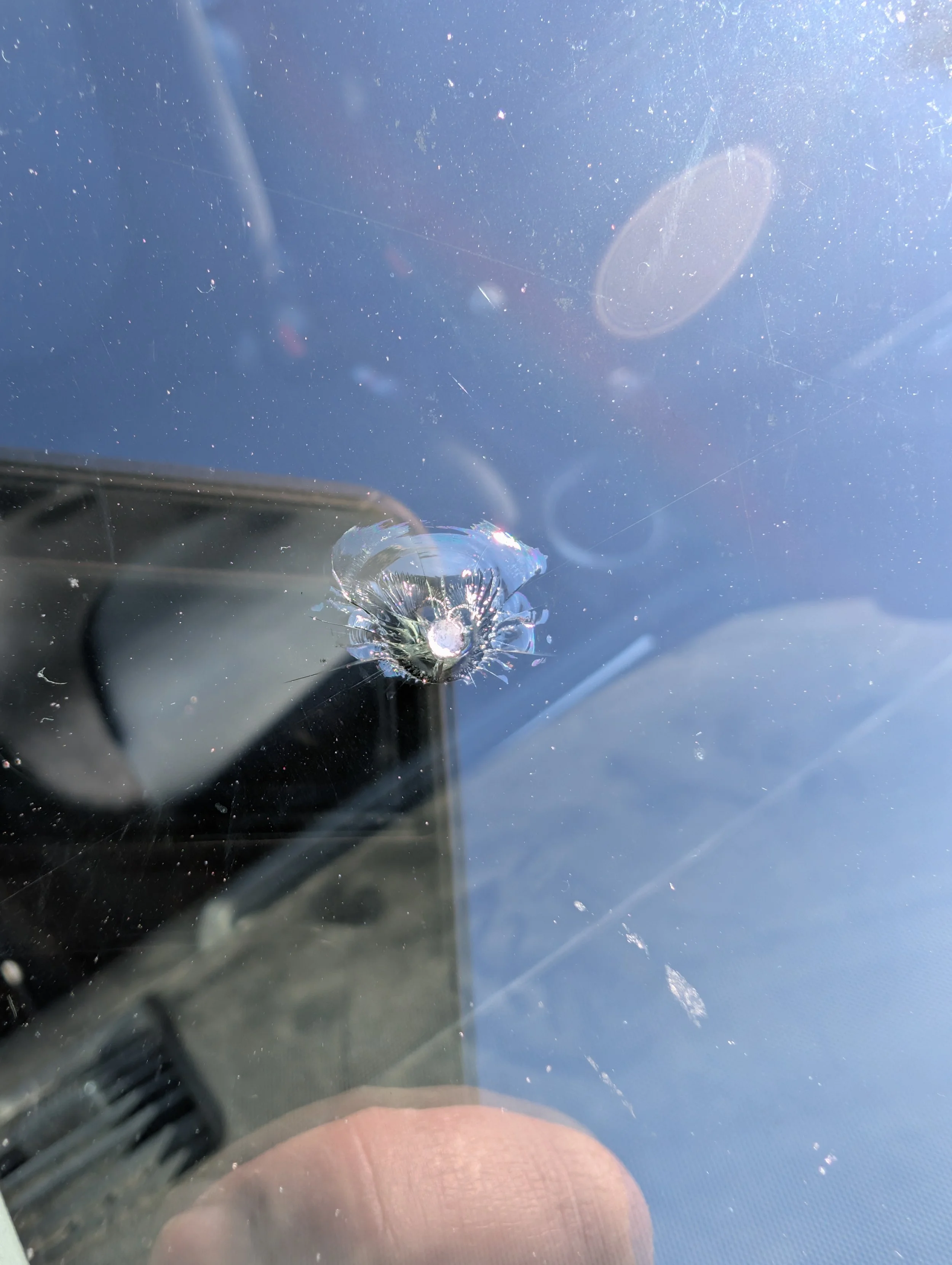 Close-up of rock chip damage on a windshield of a vehicle.