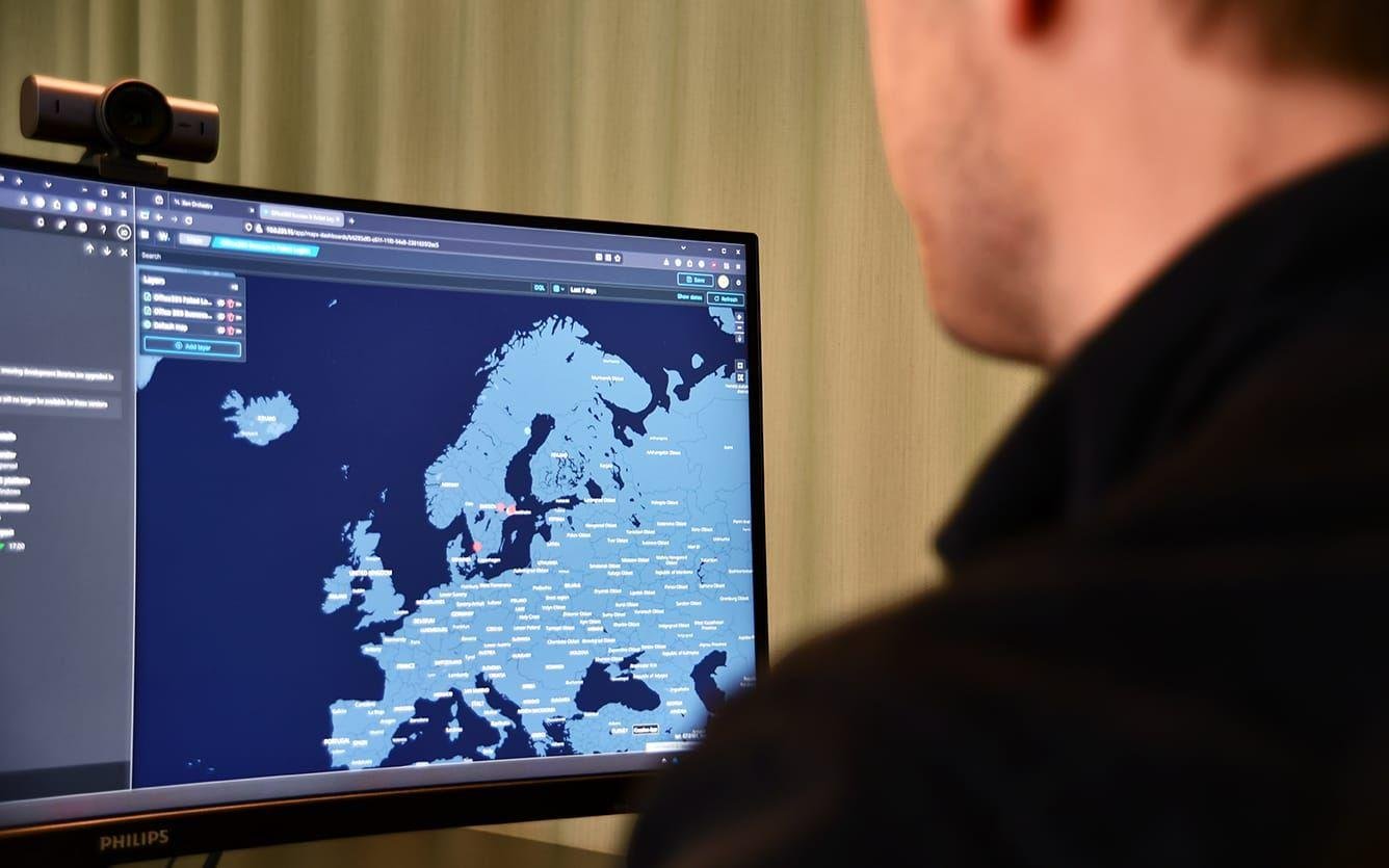 Person som tittar på en skärm med en karta över Europa och världen, visar data och regioner i ljusblått.