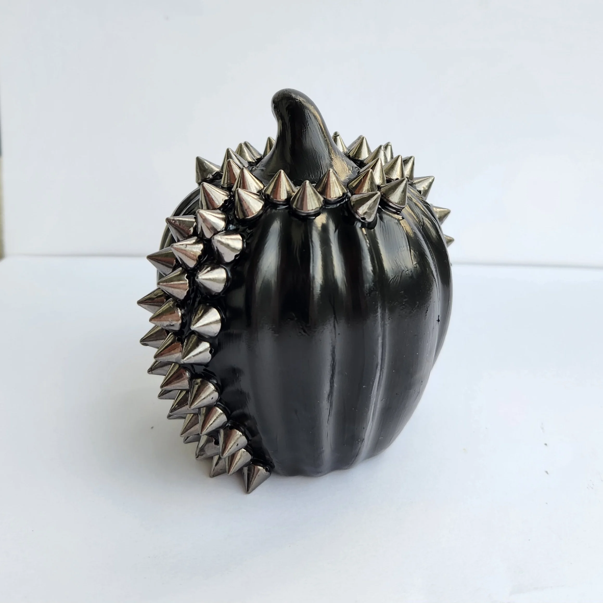 A black pumpkin with silver spikes around the stem.