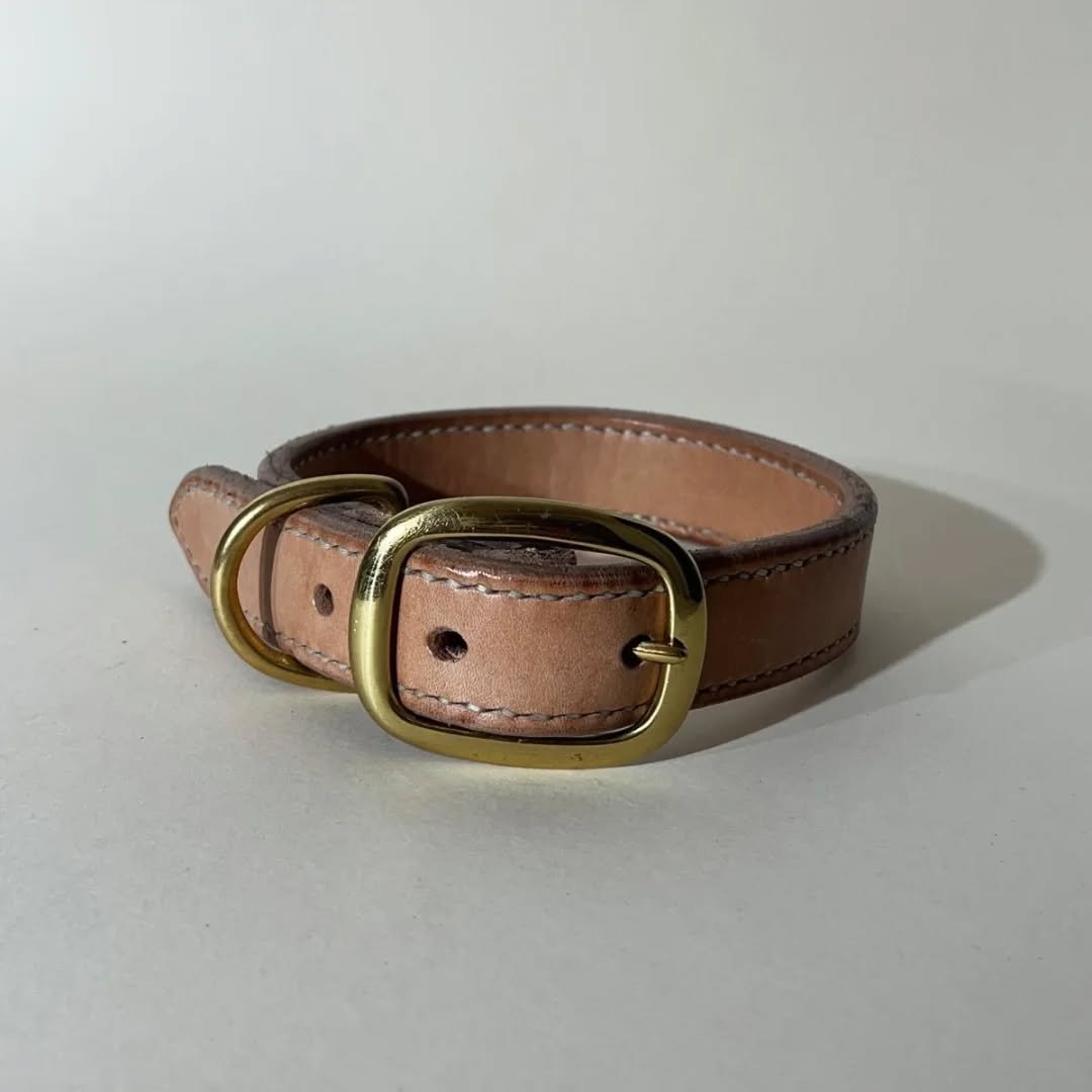 Collar.
Two layers of 2,4-2,6 mm veg. tanned leather, with a D-ring fixed between the layers and a hand stitch around the edges , making this piece sturdy and quite wear resistant.
The strap end lays on the external part of the collar, allowing a smo