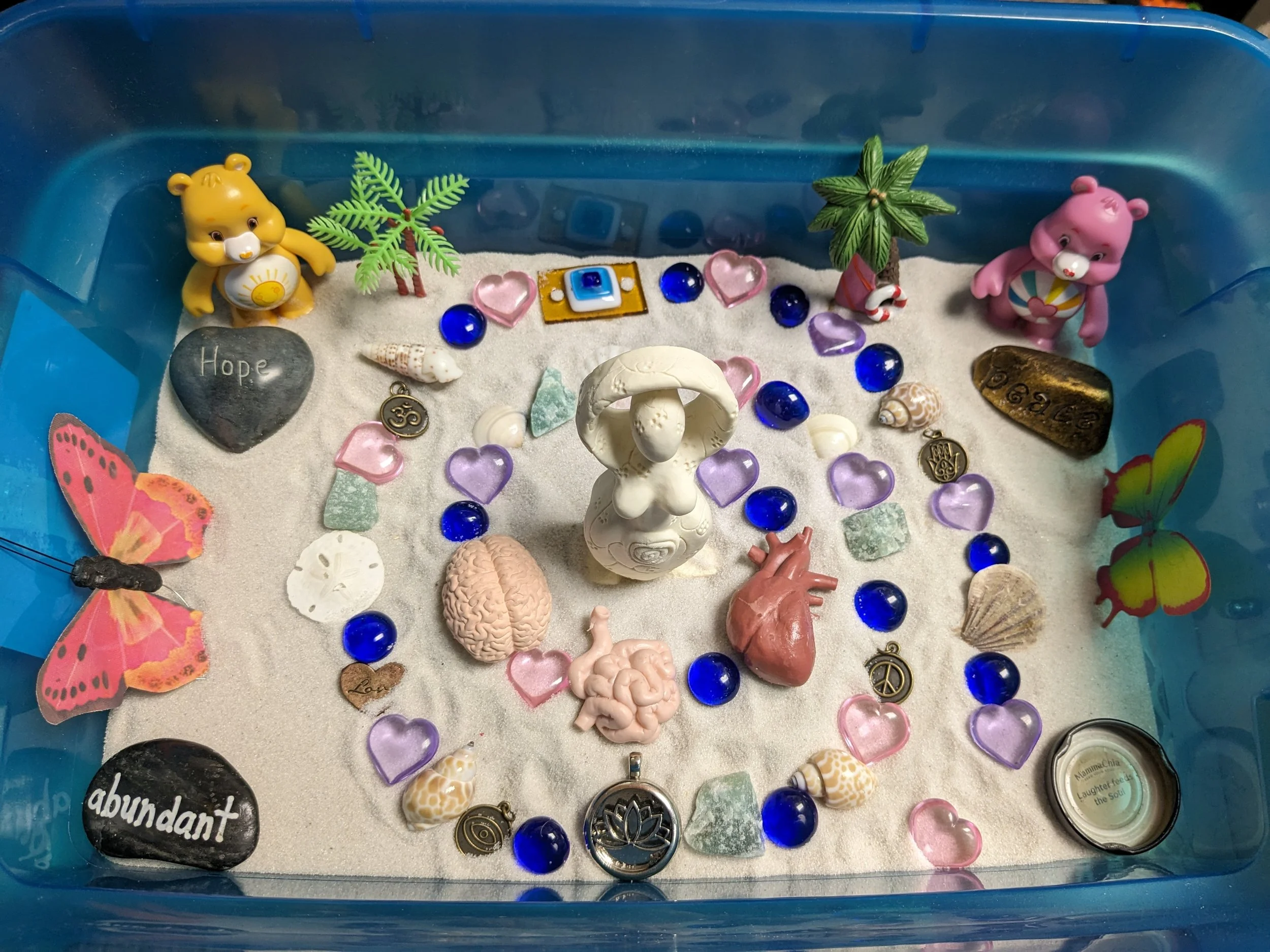 A sandtray therapy collection with miniature figures, animals, and symbolic objects used in expressive therapy sessions at Lotus Life KS