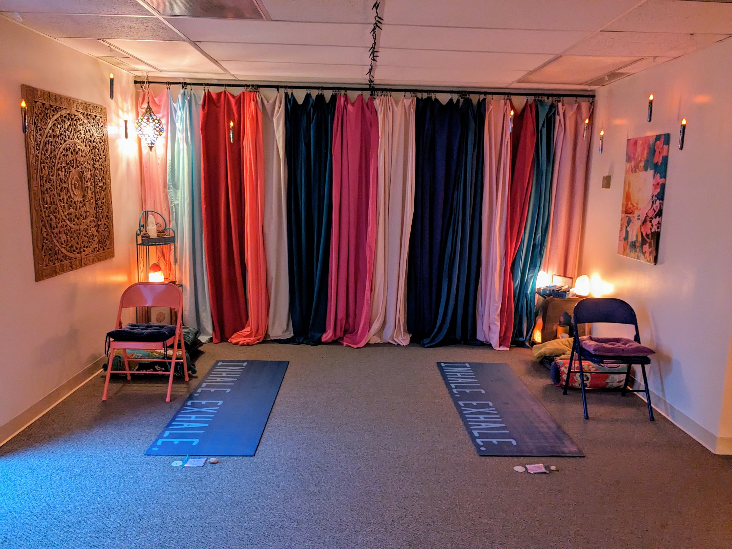 room with soft lighting and a wall of colorful fabrics with chairs and yoga mats set out for movement and breathwork for mind body connection  and address the nervous system in therapy for trauma, grief, and neurodivergent people in Olathe, Kansas