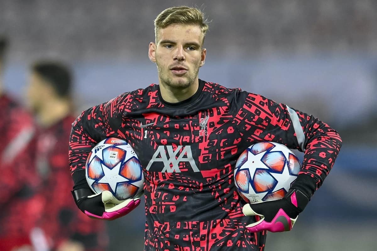 Soccer player holding two soccer balls during training, wearing a red and black geometric-patterned jersey and gloves.