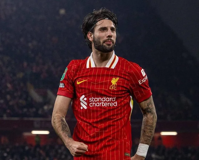 Soccer player in red Liverpool FC jersey on field.