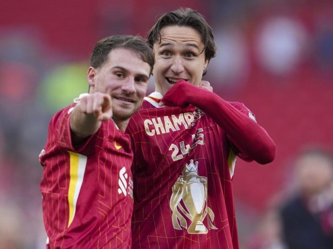 Two soccer players celebrating in red jerseys after a championship win.