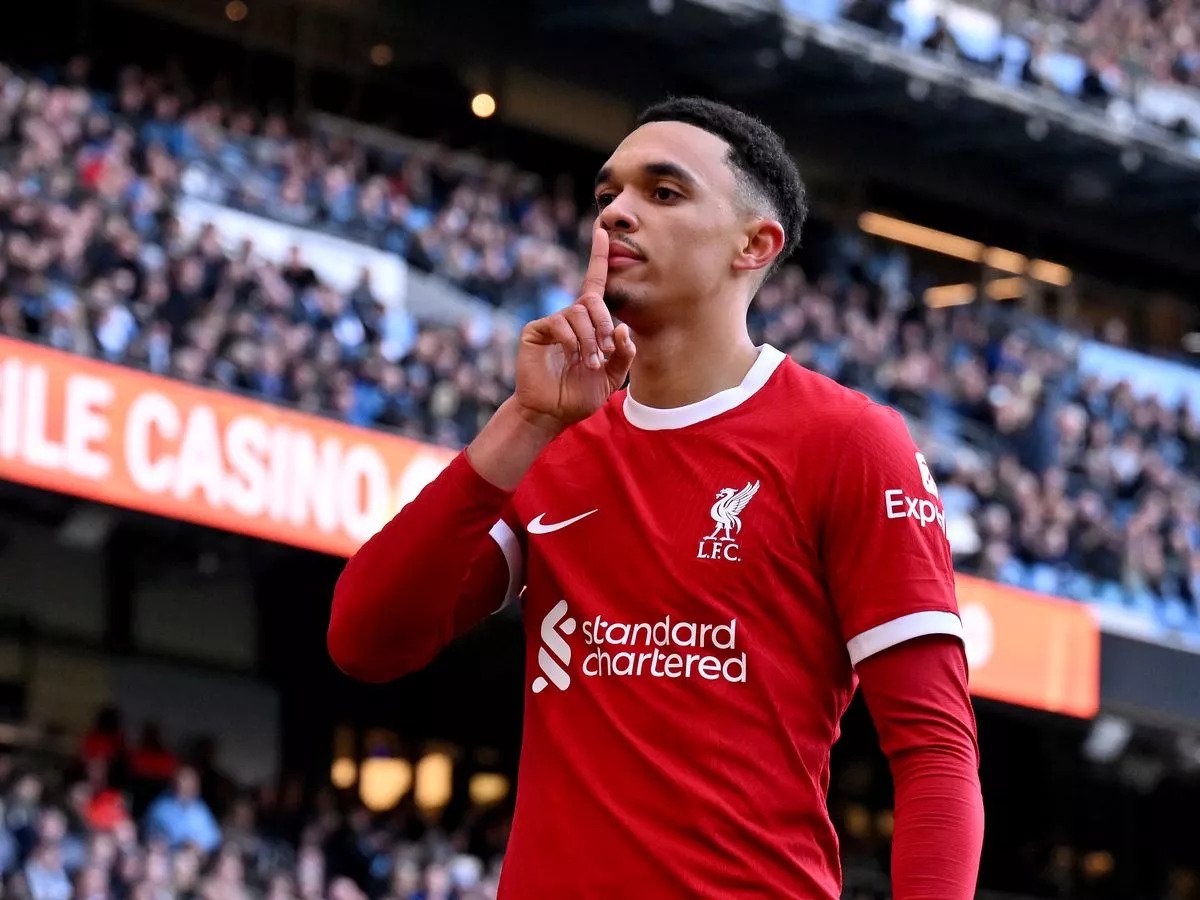 Soccer player in red Liverpool FC jersey making a shushing gesture towards the crowd.