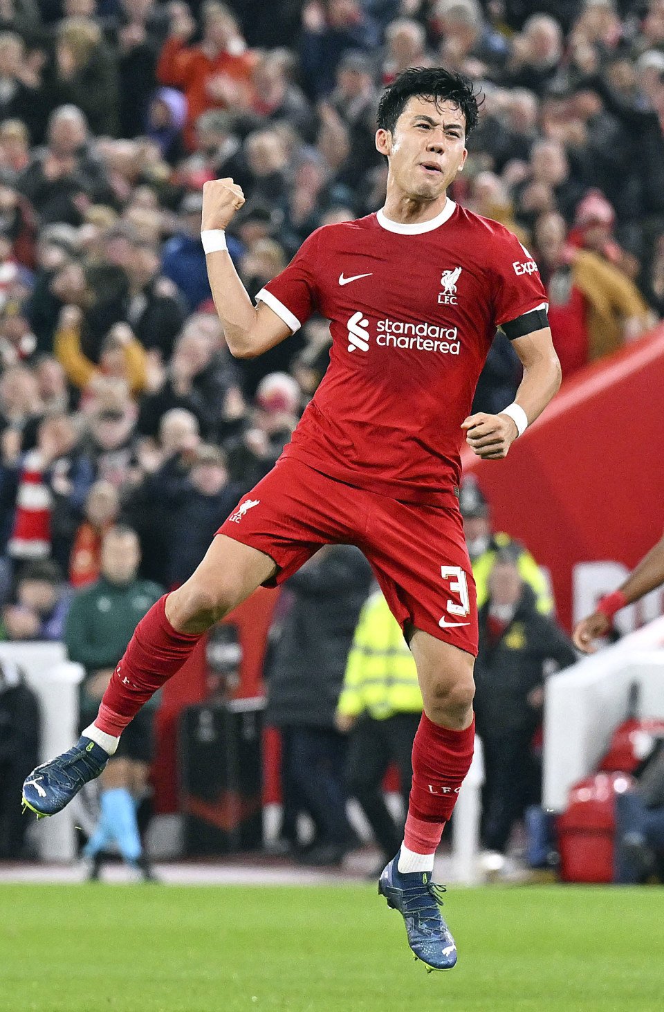 Soccer player in a red jersey celebrating on the field with a crowd in the background.